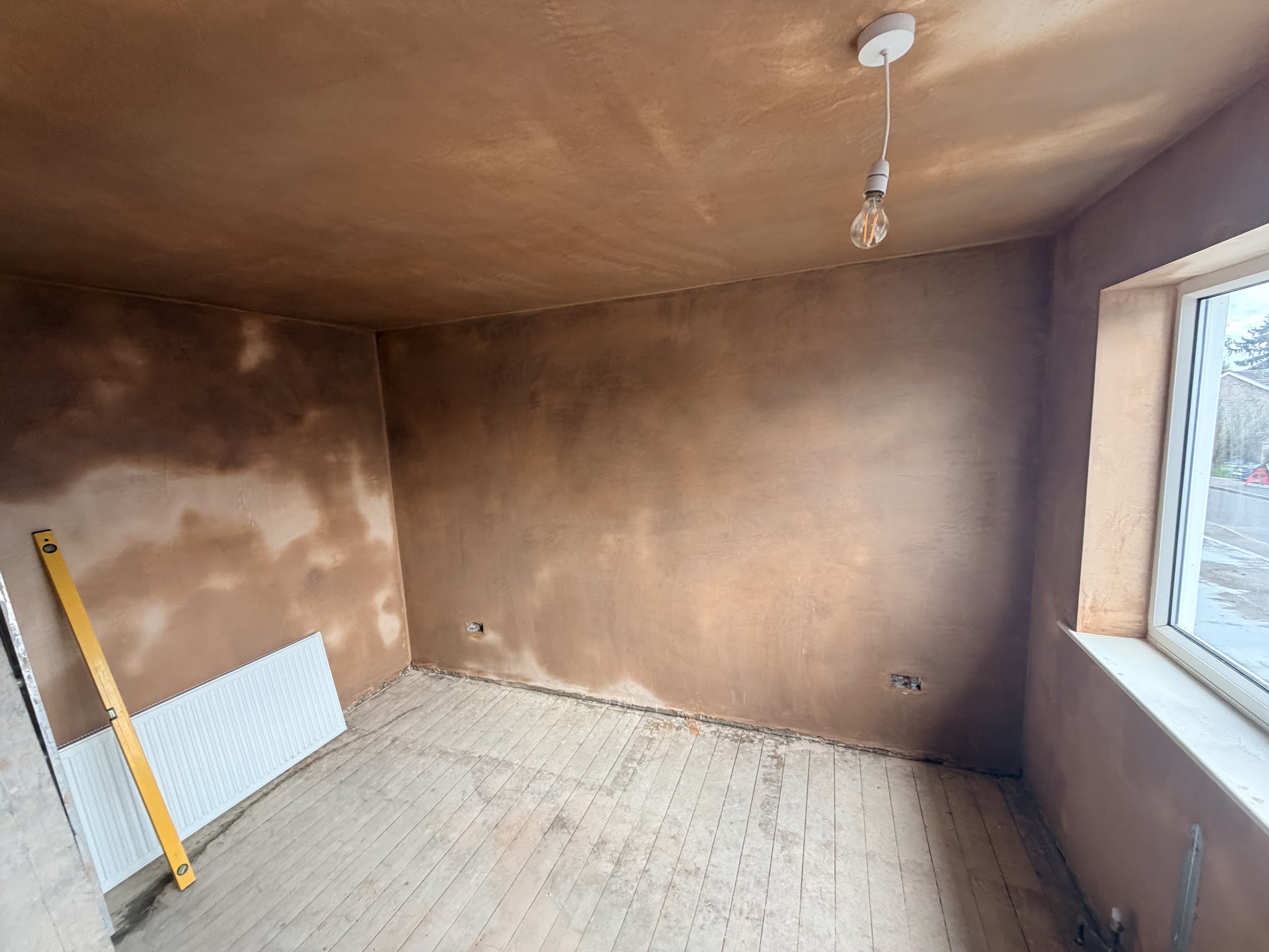 Freshly plastered room with a radiator and window, still drying